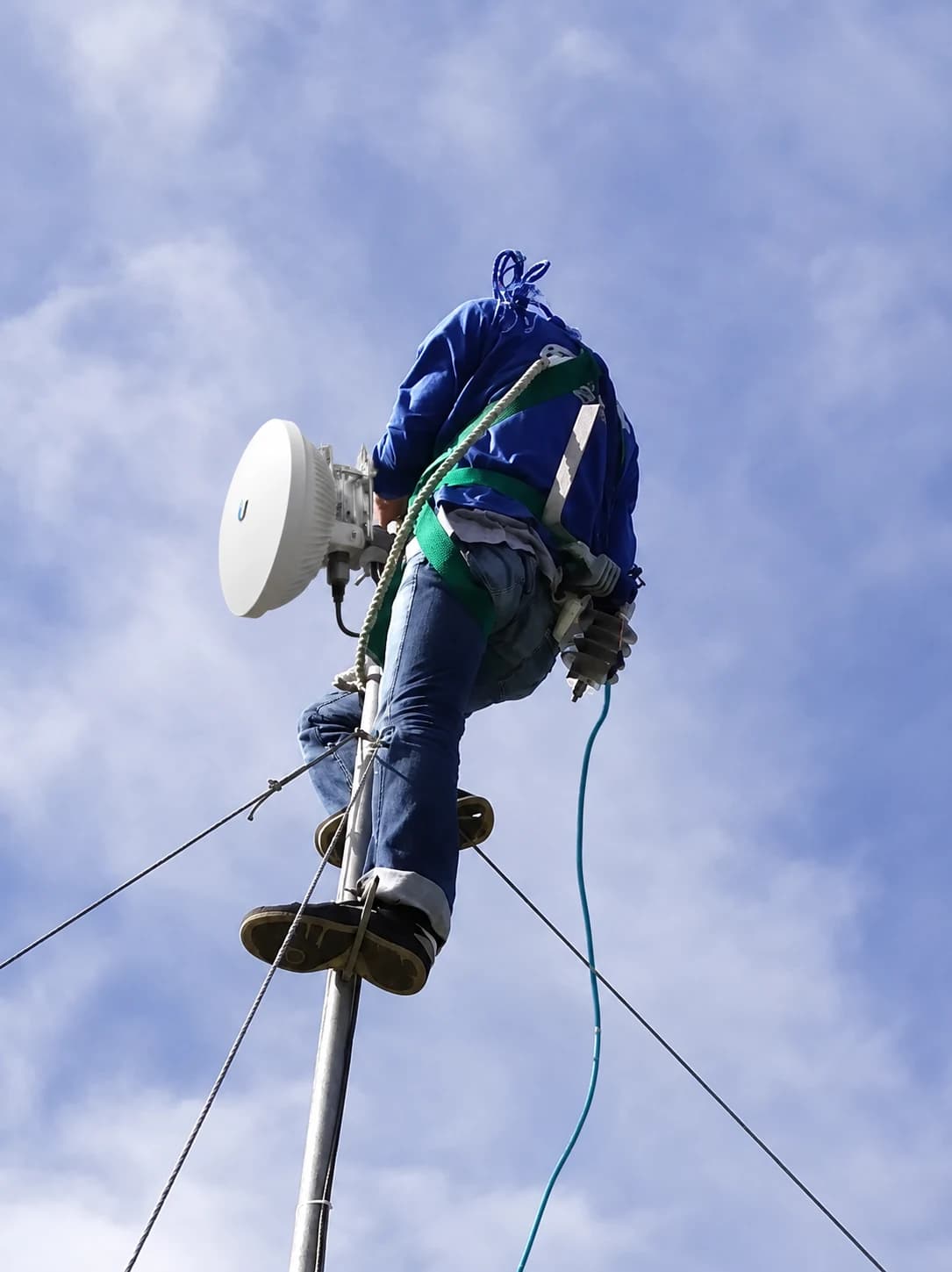 A field technician working on elevated communications equipment