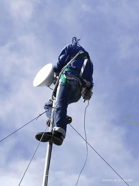 A field technician working on elevated communications equipment