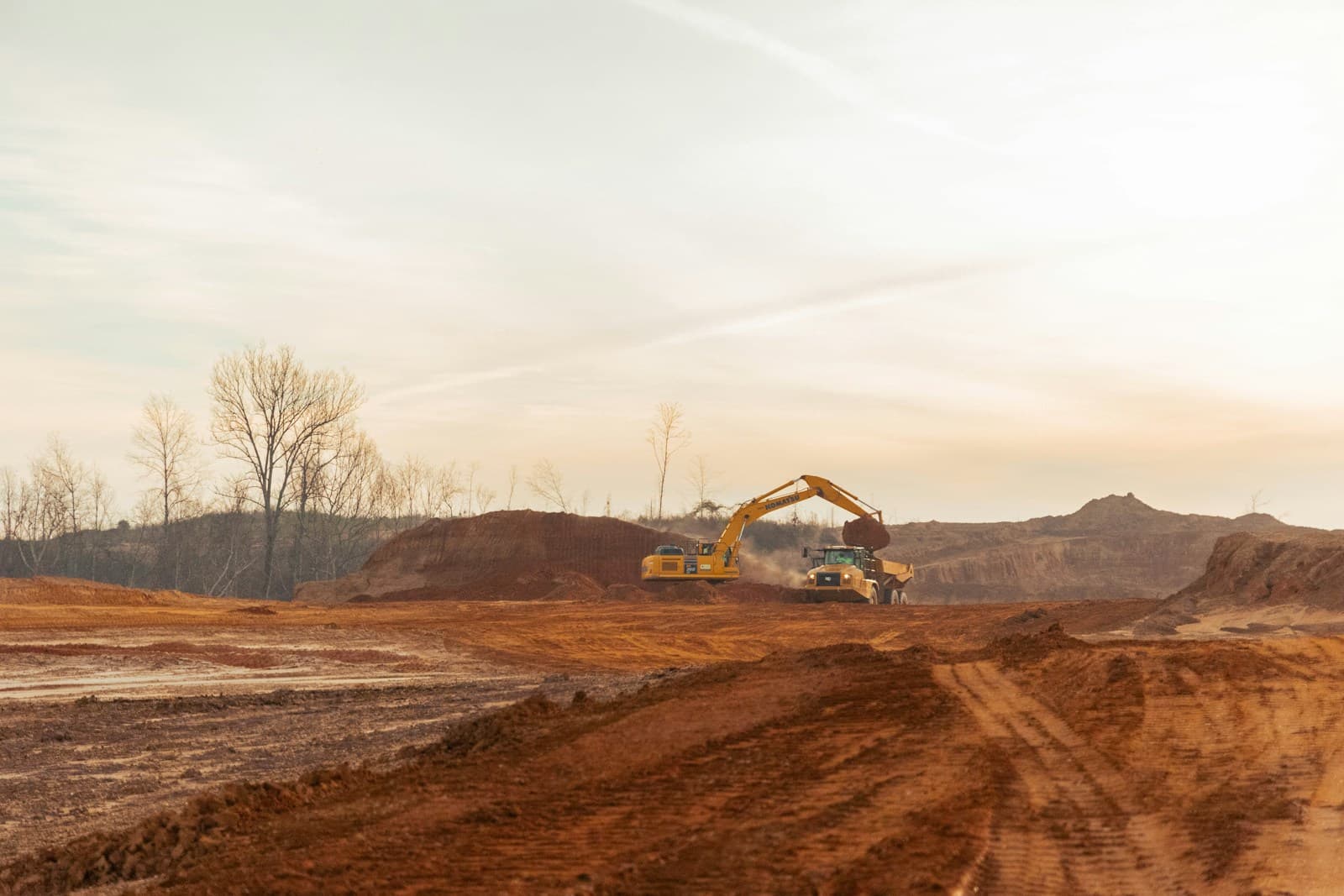 An excavator loading a dump truck at a gravel pit
