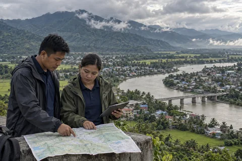 Philippine resilience planners reviewing flood exposure, editorial illustration
